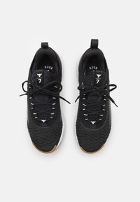 Scarpe da ginnastica nere con tomaia testurizzata, lacci bianchi e suola in gomma. Presentano un tassello per il recupero e un dettaglio del logo sulla linguetta.