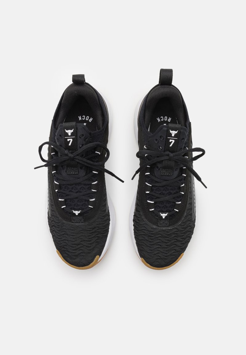 Zapatillas deportivas negras con parte superior texturizada, cordones blancos y suela de goma. Presentan una tira en el talón y un detalle de logo en la lengüeta.