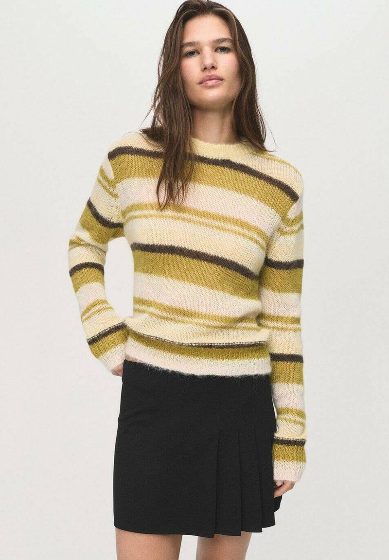 Maglione a righe giallo, verde e marrone con un design aderente e maniche lunghe, abbinato a una gonna nera plissettata. Texture morbida.
