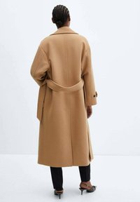 Długi, wełniany płaszcz w kolorze camel z paskiem w talii, szerokimi klapami i bocznymi kieszeniami. Charakteryzuje się lu�źnym fasonem i obniżonymi ramionami.