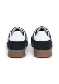 Granatowe zamszowe trampki z białymi skórzanymi akcentami i szarym tekstylnym wykończeniem. Posiadają brązową gumową podeszwę i teksturowany detal na pięcie.