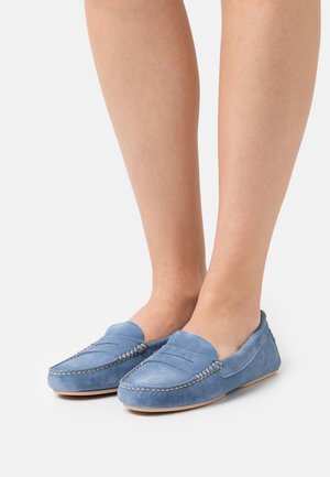 Modré semišové loafers majú klzné zapínanie s šitím, okrúhlym špičkou a textúrovaným povrchom. Podrážky sú minimálne a ploché.