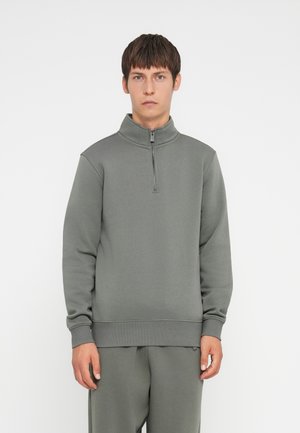 Gray sweatshirt with a high collar and half zipper. Made of a smooth, soft fabric with a relaxed fit. Cuffs and hem are ribbed for structure.