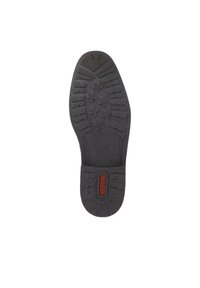 Semelle de chaussure en caoutchouc noir présentant un design texturé avec des motifs de semelles en forme de feuille et un logo central. Les nervures renforcées assurent une bonne adhérence.