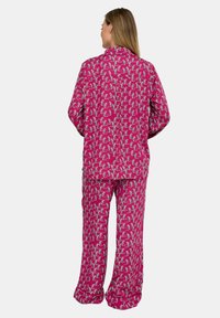 Rosa Schlafanzug-Set mit wiederholtem Tiermuster, aus weichem Stoff, mit einem Hemd mit Kragen und locker sitzender Hose.