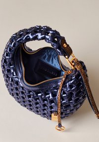 Geflochtene Navy-Tasche mit glänzender Oberfläche, strukturiertem Griff, goldener Reißverschluss und kontrastierendem blauen Innenfutter sowie einem Markenschild im Inneren.
