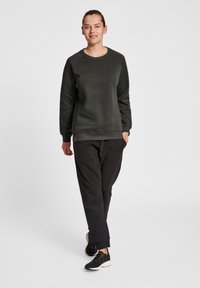 Mörkgrå sweatshirt med rundad hals, texturerat tyg och raglanärmar, matchad med svarta sweatpants och svarta träningsskor.