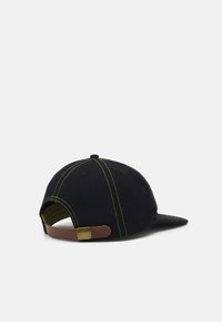 Black cap with yellow stitching, flat brim, and a brown leather strap at the back. Features a green interior lining.