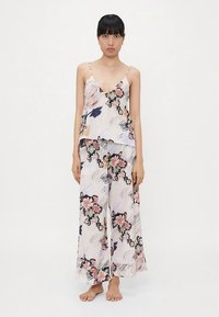 Conjunto floral de duas peças feito de tecido leve; apresenta um top sem mangas com decote em V e calças largas e fluídas com um padrão floral colorido.