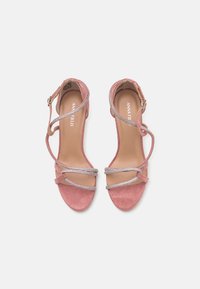 Sandales à talons hauts en suède rose avec des multi-brins, ornées de détails argentés, dotées d'une sangle à la cheville et d'un design à bout ouvert.