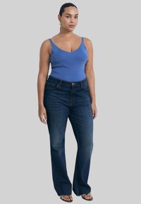 Blue ribbed tank top with thin straps, paired with dark blue flared jeans. The jeans feature a button closure and subtle fading on thighs.