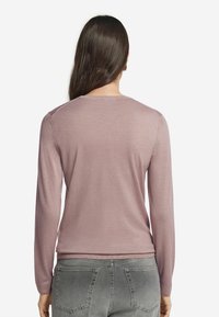 Ljust rosa långärmad tröja med rund halsringning och ribbade manchetter. Mjuk textur, enkel design, passar bra till grå denimjeans.