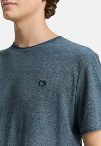 Sötétkék, rövid ujjú póló, puha, textúrált anyagból készült, kis sötét logóval a bal mellrészen.