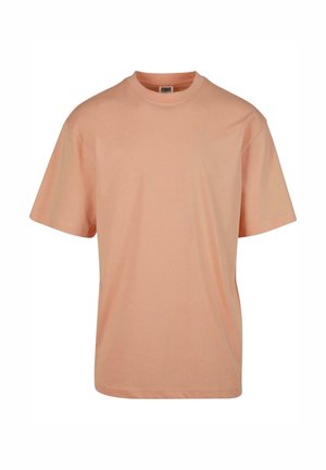 Tricou cu mânecă scurtă și gât rotund, de culoare piersiciu deschis, realizat dintr-un material moale din bumbac cu o textură fină și o croială relaxată.