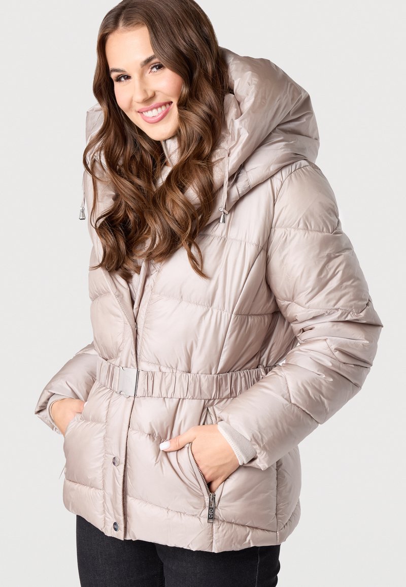 Helle beigefarbene Daunenjacke mit tailliertem Schnitt, großer Kapuze und Reißverschlusstaschen. Verfügt über eine gesteppten Textur und silberne Hardware-Akzente.