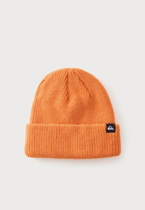 Bonnet en tricot côtelé orange avec un revers plié et un petit patch logo rectangulaire noir sur le revers, sur un fond uni.