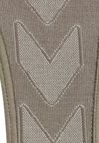 Textil med ett zigzagmönster i ljus och mörk beige. Ytan har en texturerad väv, med kontrasterande sömdetaljer längs kanterna.
