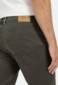 Dunkelgrüne Baumwollhosen mit einem Leder-Logopatch und normalen Gesäßtaschen mit dezenten Steppdetails.