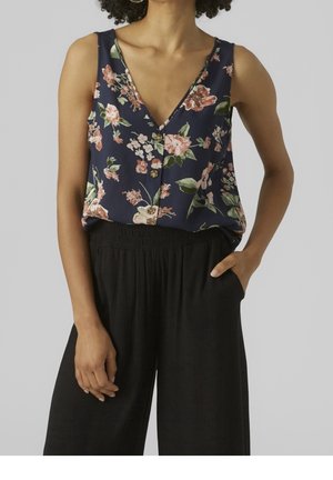 Top senza maniche con motivo floreale in tessuto blu navy, caratterizzato da una profonda scollatura a V, con piccoli bottoni. Abbinato a pantaloni neri strutturati.