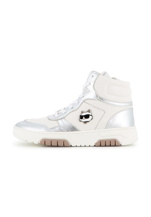 Basket blanche montante avec des accents argentés et un petit logo chat noir portant des lunettes de soleil sur le côté. Lacets blancs et semelle marron crantée.
