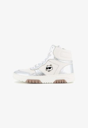 Basket blanche montante avec des accents argentés et un petit logo chat noir portant des lunettes de soleil sur le côté. Lacets blancs et semelle marron crantée.
