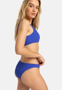 Two-piece bikini set in textured ribbed material, featuring a vibrant blue color, thin straps, and a classic bikini bottom design.