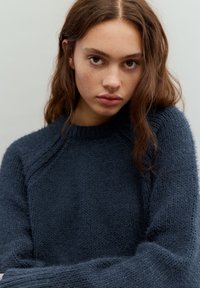 Tengerészkék kötött pulóver bordázott kerek nyakkal és texturált kivitelben. Látható varrásokkal és laza szabással rendelkezik.