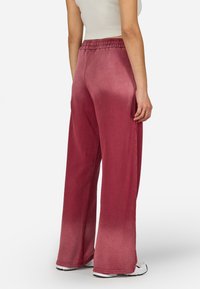 Plati svārki dziļi sarkanā audumā ar elastīgu jostasvīru. Audumam ir nedaudz teksturēta virsma un gradienta apdare uz apakšmalas.