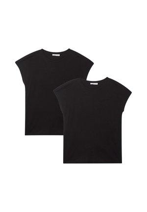 Maglietta nera in cotone a maniche corte con scollo rotondo, abbinata a leggings neri. Completato con scarpe da ginnastica bianche.