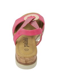 Sandalo rosa con design a strappo incrociato, caratterizzato da un accento circolare e suola in sughero. Il materiale superiore è sintetico texturizzato.