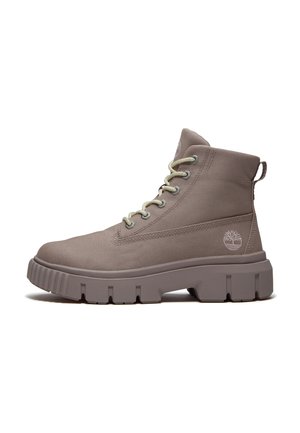 Taupe høj-top støvle med chunky sål, tekstiloverdel, snørebånd foran og Timberland trælogo på hælsiden.