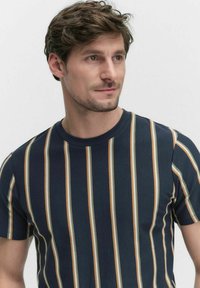 Marineblauwe T-shirt met korte mouwen, voorzien van verticale strepen in crème en roestkleur. Gemaakt van gestructureerde stof en heeft een ronde hals.