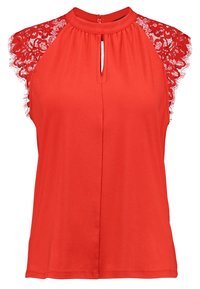 Haut rouge sans manches avec un col montant, présentant des accents en dentelle sur les épaules et un détail à ouverture en forme de trou de serrure à l'avant. Texture douce et lisse.