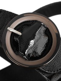 Close-up of a black patent leather belt with a round translucent buckle and a silver metal pin.