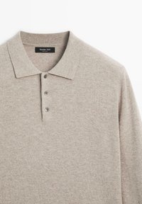 Ljusbeige långärmad polo med tre knappar och spetsig krage, med Massimo Dutti-märket synligt inuti halsringningen.