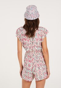 Patroon romper met korte flutter mouwen, elastische tailleband en multicolore ikat ontwerp. Gecombineerd met een bijpassende bucket hat.