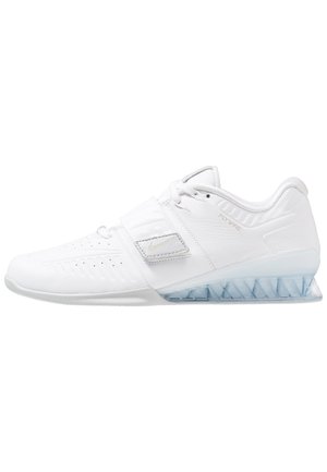 Hvid atletiksko med snørebånd og remlukning, tekstureret syntetisk overdel samt gennemsigtig trekantet polstring på sålens hælsektion.