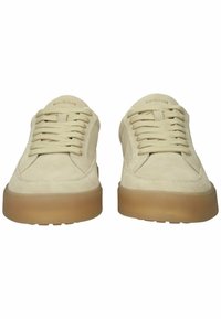 Beige suède vetersneakers met dikke doorschijnende bruine rubberen zolen, voorkant gezien.