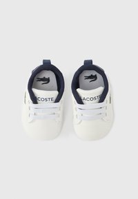 Λευκά παιδικά αθλ ητικά παπούτσια με ναυτικό μπλε λεπτομέρειες, με κορδόνια, λαστιχένιες σόλες και κεντημένο λογότυπο στο πλάι. Μαλακή υφασμάτινη επένδυση στο εσωτερικό.