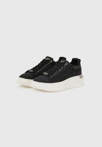 Zwarte sneakers met een gestructureerd patroon, vetersluiting en een witte rubberen zool. Voorzien van een klein metallic accent op de hiel.