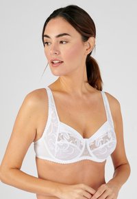 Witte beha met kantdetails, verstelbare bandjes, een golvende rand en ondersteuning met beugel. Gladde stof met bloemenborduursels.