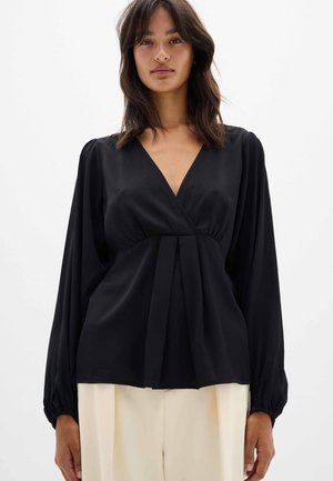Black wrap blouse with a deep V-neck, long puff sleeves, and pleated detailing at the waist. Made of smooth, lightweight fabric.