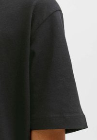 Zwart katoenen T-shirt met een ontspannen pasvorm, korte mouwen en nette stiksels. De stof heeft een gladde textuur met een lichte rek.