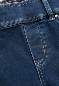 Donkerblauwe denimstof met een egale textuur, voorzien van zichtbare stiksels en een zakdetail, die een klassieke jeansontwerp laat zien.