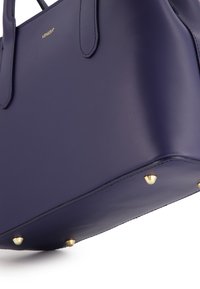 Navyblaue Lederhandtasche mit goldenen Hardware-Akzenten, ausgestattet mit zwei oberen Griffen und Schutzfüßen am Boden. Glatte Textur.
