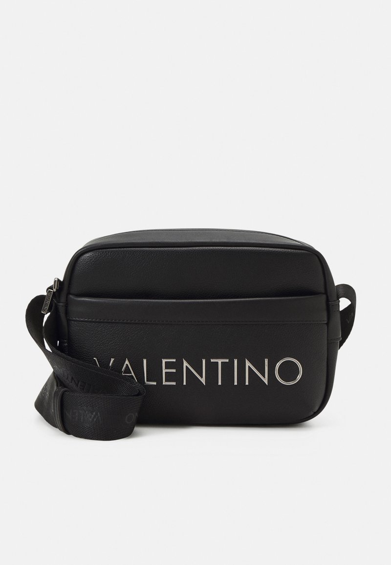 Black leather crossbody bag with silver "Valentino" logo, rectangular shape, adjustable strap, and smooth texture. Zipper closure on top.