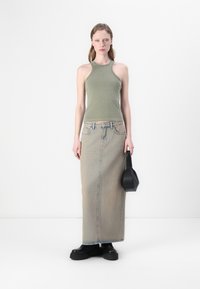 Zelena majica bez rukava i svijetloplava denim maxi suknja. Crne platforme. Mala crna torbica sa strukturiranim dizajnom. Minimalistička pozadina.