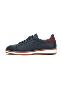 Zapatillas de cuero con parte superior en color marino, acento burdeos en el talón y media suela blanca. Presenta cordones oscuros y una superficie texturizada.