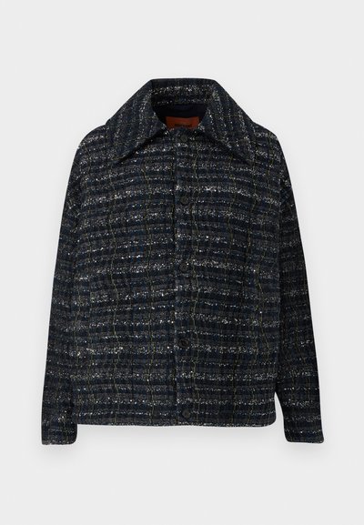 Tweedowa kurtka w ciemnoniebieskim kolorze w kratkę. Posiada spiczasty kołnierz i guziki z przodu. Tekstura wydaje się tkana i lekko błyszcząca.