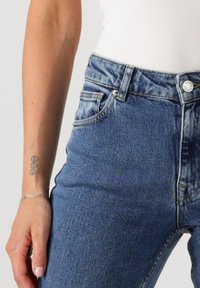 Höga blå denimjeans med en urtvättad finish, med fem fickor, metallknäppning och kontrasterande sömmar.